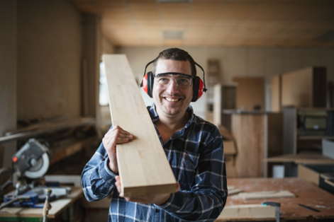 Worker holding piece of lumber over his shoulder 